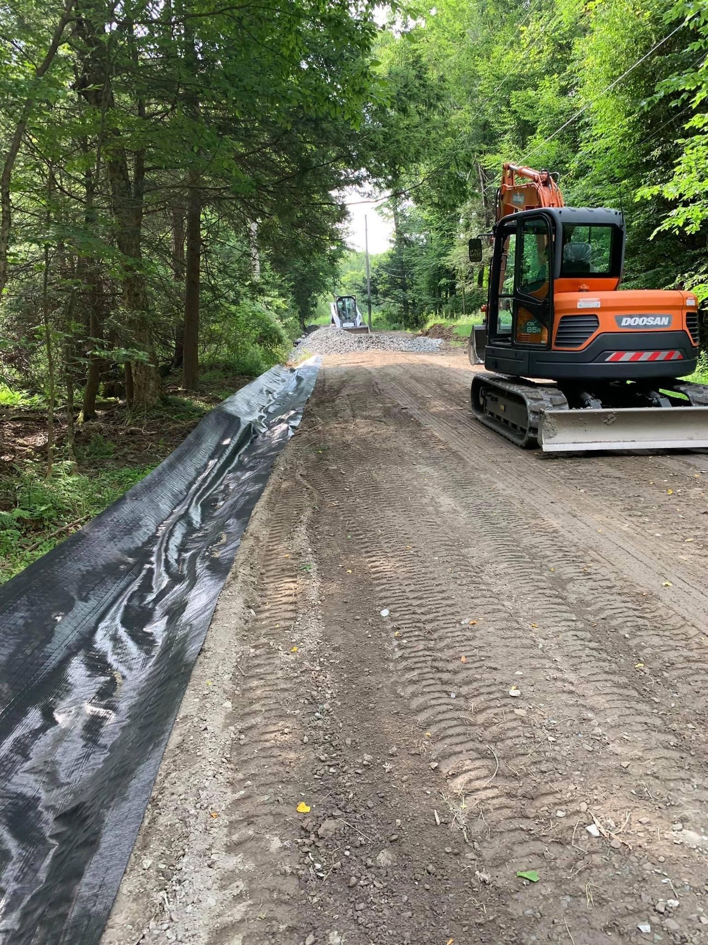 Excavator regrading driveway on gravel pond road , Clark’s summit